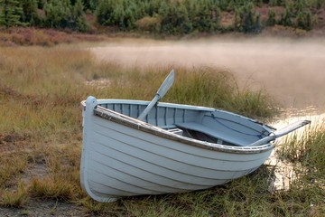 Rowboat at edge of mist-covered pond in Alaska 