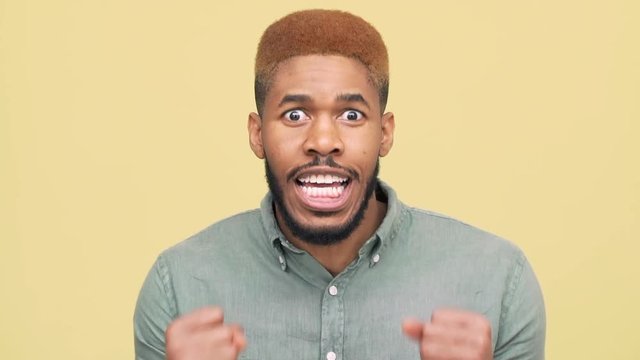 reaction of tense metis man feeling delight like winning lottery after stressful waiting over yellow background closeup in slow motion. Concept of emotions