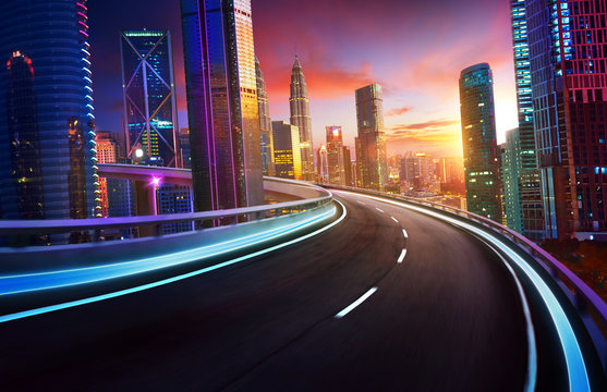 Highway overpass motion blur with city skyline and urban skyscrapers , sunset and twilight scene.