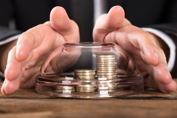 Person Hands Covering Coins In Bowl