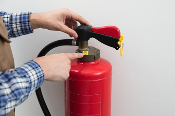 Technician's Hand Pointing To Symbol On Red Fire Extinguisher