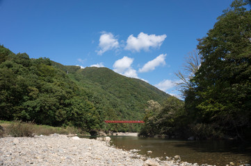 Fototapeta na wymiar 秋田県　抱返り渓谷　赤い吊り橋　青空