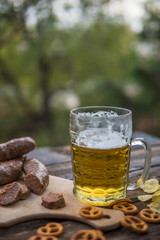 Beer, sausages and pretzels on the wooden board outdoor. Octoberfest theme
