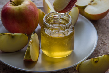 Organic honey in glass jar and red apple on the plate