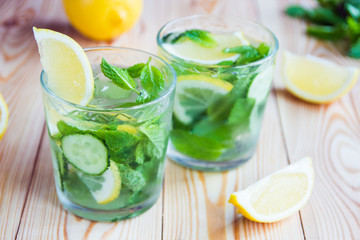 Detox water, fresh organic lemonade with ice, cucumber, lemon and mint on wooden background