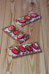 Wholegrain rye crispbread crackers with cream cheese, strawberry and arugula