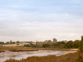 Fototapeta na wymiar river channel horizon sky scene with essex university towers in distance and cranes