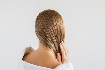 Femme dans la serviette blanche touchant ses cheveux blonds mouillés après la douche sur le fond gris. Se soucie d& 39 un cheveu sain et propre. Notion de salon de beauté.