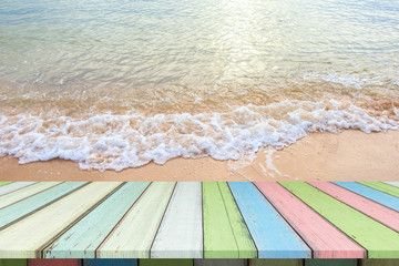 Empty wooden table or plank with sand beach and sea wave on background for product display.