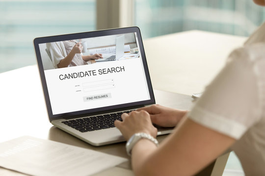 Casual businesswoman searching for job candidate using search engine on laptop. Employer searches for new professional staff. Headhunter browsing resumes. Close up view over shoulder, focus on screen.