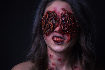 Girl with realistic sores and worms in her eyes. Creative halloween makeup.