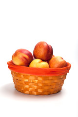 Basket full of fresh peaches isolated on white background