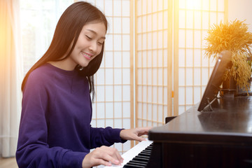 Lovely teen playing piano in the music room.