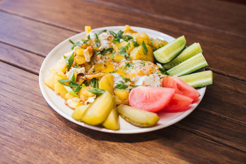 Fried potatoes with egg, fresh cucumbers and tomatoes