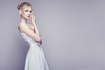 Fashion portrait of Beautiful Young Woman with Blond Hair. Girl in white Dress on White Background