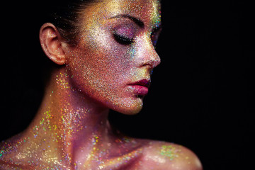 Portrait of Beautiful Woman with Sparkles on her Face. Girl with Art Make-Up in Color Light. Fashion Model with Colorful Makeup