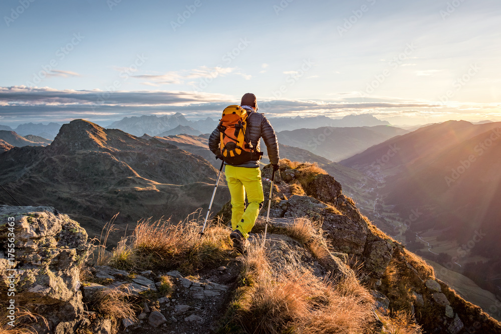 Wall mural mountaineer hiking in the mountains in morning light