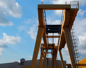 Gantry cranes seen from below against blue sky with clouds