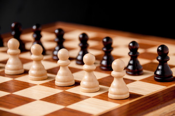 Still life on the chessboard: white and black pawns stand in a row