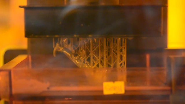 Stereolithography DPL 3d printer create detail and liquid drips, platform slowly move with liquid close-up. Progressive modern additive technology 3D printing, create scaled model by UV polymerization
