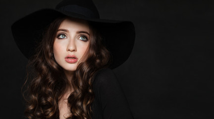 Beautiful Brunette Woman with Perfect Curly Hairstyle and Makeup. Perfect Model wearing Black Hat