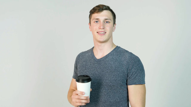 Young Man Drinking Coffee From Disposable Paper Cup On White Background