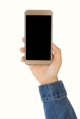 Hand wearing jeans jacket holding gold smartphone, with blank screen. Isolated on white background.
