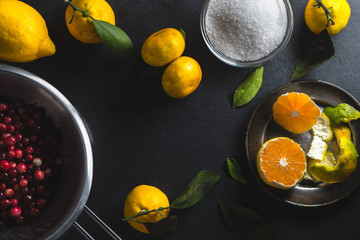 Frame of tangerines, lemon and cranberries on a gray table