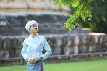 Fototapeta premium Thai woman wearing traditional Thai dress with old temple background