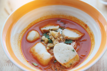 Fish and fishball Tom yum noodle on wood background , Thai food