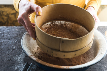 Sifting cocoa into a bowl with flour view from the side