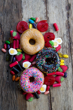 unhealthy but delicious group of sweet sugar donut cakes and lots of gummy candies on vintage wooden table