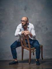 A man in a white shirt is dancing with an old wooden chair.