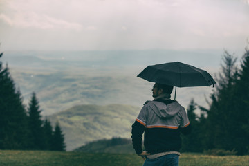 Hiker man holding umbrella in nature.