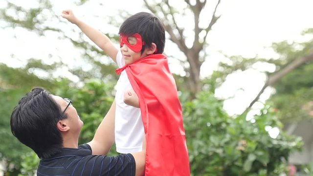 Asian father and his son playing together in the park,Boy in Superhero's costume.slow motion 