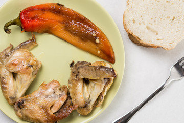 Flat lay above fried chicken wings with fried paprika served on the plate with bread and fork