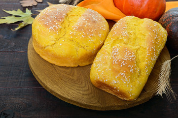 Golden homemade freshly baked pumpkin bread with sesame seeds on a dark wooden background.