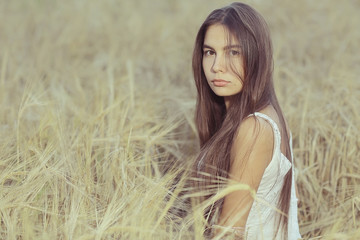 Fototapeta na wymiar Dreaming in a wheaten field beautiful young adult woman