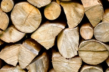 Abstract photo of a mixture of symmetric and asymmetric pile of natural wooden logs background, top view.