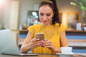 Woman using mobile phone at cafe
