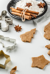 Christmas baking. Ginger dough for gingerbread, gingerbread men, stars, Christmas trees, rolling pin, spices (cinnamon and anise), flour. On the home kitchen white marble table. Copy space