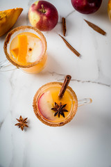 Halloween, Thanksgiving. Traditional autumn, winter drinks and cocktails. Spicy hot pumpkin sangria, with apple, cinnamon, anise. On a white marble table, in glass mugs. Top view copy space