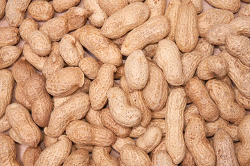 Peanuts in a peel against a light wood background