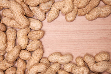 Peanuts in a peel against a light wood background