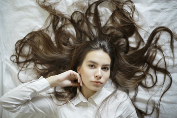 Fototapeta premium brunette with long hair outstretched on the bed