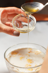Adding honey to morning porridge with milk and dried fruits