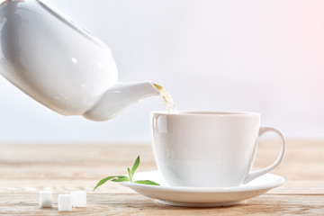 Pouring green tea from white ceramic teapot