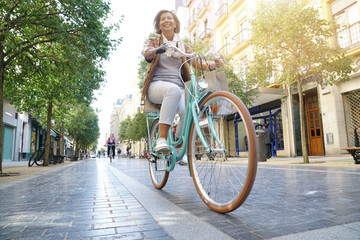 Senior woman riding city bike in town - Powered by Adobe