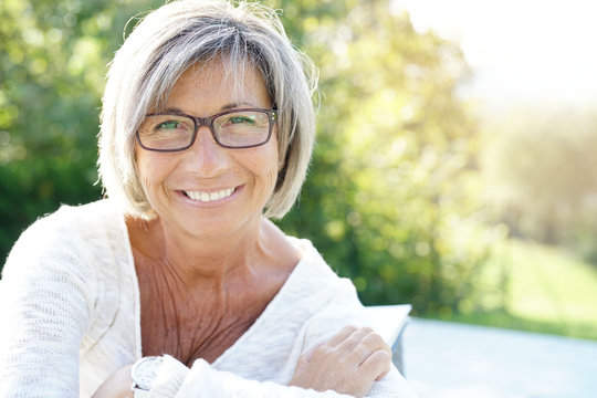 Cheerful mature woman with eyeglasses relaxing outside