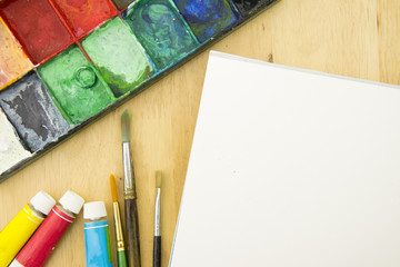 Artist paint brushes and palette on wooden background